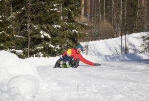 man-and-son-tobogganing-in-snow-covered-forest-2024-06-26-20-54-48-utc